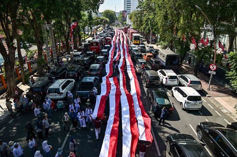 Ribuan pelajar dari berbagai sekolah di Surabaya membentangkan bendera merah putih sepanjang 14. 905 meter di di Jalan Gubernur Suryo Surabaya, Minggu (17/08/2025).