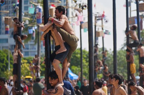 Peserta memanjat batang pinang saat lomba memperingati Kemerdekaan RI di Beach Pool, Ancol Jakarta, Minggu (17/08/2025
