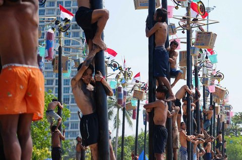 Peserta memanjat batang pinang saat lomba memperingati Kemerdekaan RI di Beach Pool, Ancol Jakarta, Minggu (17/08/2025