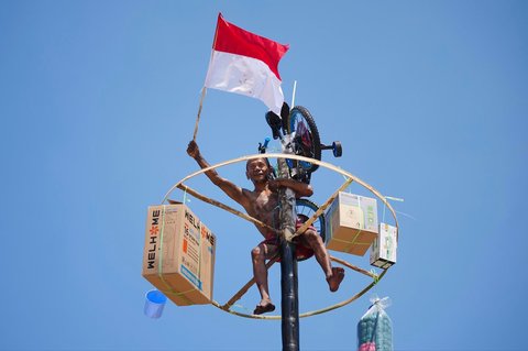 Peserta mengibarkan bendera merah putih usai memanjat batang pinang saat lomba memperingati Kemerdekaan RI di Beach Pool, Ancol Jakarta, Minggu (17/08/2025