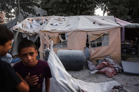 Warga Palestina berkumpul di dekat tenda pengungsian yang rusak akibat serangan Israel terhadap sebuah gedung enam lantai di lingkungan Saftawi, sebelah barat Jabalia, Jalur Gaza utara, Selasa (19/08/2025) waktu setempat.