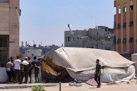 Warga Palestina menyaksikan roket yang ditembakkan pesawat tempur Israel menyasar sebuah gedung di Jabalia, Jalur Gaza utara, Rabu (20/08/2025). <br />AFP/ Bashar Taleb