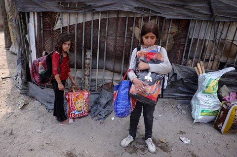 Anak-anak Palestina berdiri di samping barang-barang keluarga mereka saat mereka bersiap mengungsi dari permukiman Abu Iskandar di utara Kota Gaza,  Palestina, Jumat (22/08/2025).
