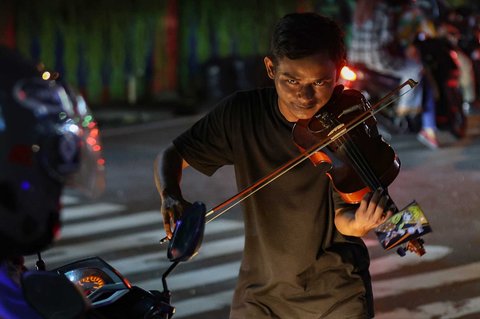 Pengamen Kris Violist di perempatan Juanda, Depok, Jumat malam (22/08/2025).