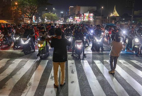 Pengamen Kris Violist dan istrinya saat memainkan musik biola di perempatan Juanda, Depok, Jumat malam (22/08/2025).