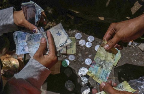 Pengamen Kris Violist dan istrinya menghitung uang recehan  di perempatan Juanda, Depok, Jumat malam (22/08/2025).