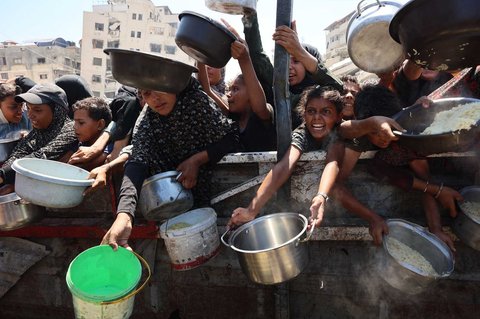 Warga Palestina mengulurkan panci kosong mereka untuk menerima nasi dari dapur amal di Kota Gaza, Sabtu (23/08/2025).