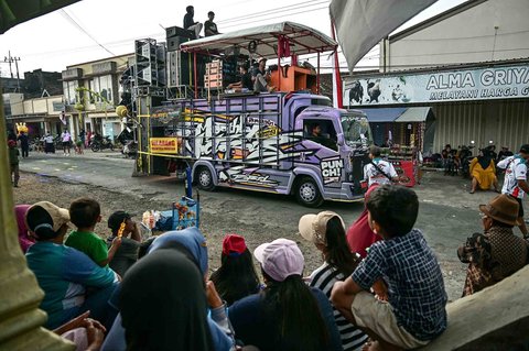 Warga menonton truk yang dipasangi menara subwoofer dan lampu sorot saat kegiatan sound horeg menyambut perayaan Hari Kemerdekaan Indonesia ke-80 di Malang, Jawa Timur (09/08/2025).