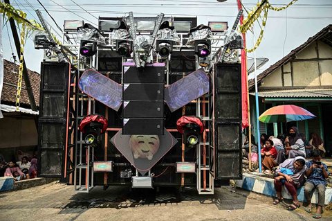 Warga menonton truk yang dipasangi menara subwoofer dan lampu sorot saat kegiatan sound horeg menyambut perayaan Hari Kemerdekaan Indonesia ke-80 di Malang, Jawa Timur (09/08/2025).
