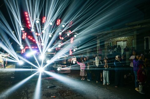 Warga menonton truk yang dipasangi menara subwoofer dan lampu sorot saat kegiatan sound horeg menyambut perayaan Hari Kemerdekaan Indonesia ke-80 di Malang, Jawa Timur (09/08/2025).