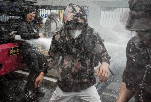 Pengunjuk rasa bertahan di tengah tembakan water canon saat demo menuntut pembubaran DPR di depan Gedung DPR/ MPR, Jakarta, Senin (25/08/2025).