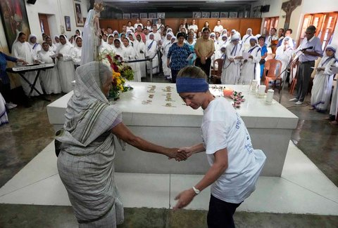 Seorang relawan dari luar negeri membantu seorang perempuan Katolik lanjut usia untuk mengikuti doa di makam Santa di Kolkata, India, Selasa, (26/08/2025).
