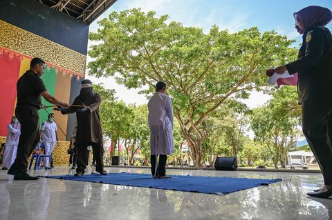 Seorang pria menunggu hukuman cambuk di depan umum oleh anggota polisi syariat di Banda Aceh, Selasa (26/08/2025).