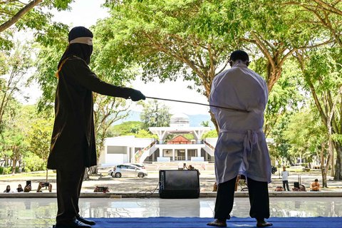 Seorang pria menjalani hukuman cambuk di depan umum oleh anggota polisi syariat di Banda Aceh, Selasa (26/08/2025).