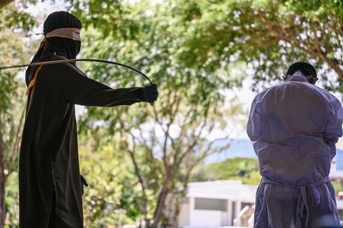 Seorang pria menjalani hukuman cambuk di depan umum oleh anggota polisi syariat di Banda Aceh, Selasa (26/08/2025).