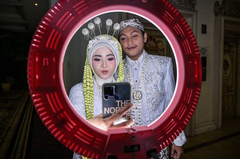 Sepasang pengantin berswafoto dalam acara Isbat nikah massal 2025 yang diselenggarakan Pemerintah Kota Surabaya di Grand Empire Palace Hotel Surabaya, Rabu (27/8/2025).