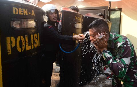 Anggota Brimob mengucurkan air ke anggota Kostrad  untuk mengurangi rasa perih akibat gas air mata  di Mako Brimob, Kwitang, jakarta, Jumat (29/08/2025).