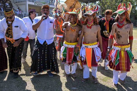 Para pria Manggarai bernyanyi dan menari saat mengikuti Caci yaitu ritual adu cambuk  di Stadion Galing Surabaya, Minggu (03/08/2025).