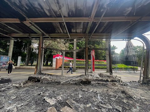 Pejalan kaki melewati halte yang hangus terbakar di Jalan Sudirman, Jakarta,  Sabtu (30/8/2025).