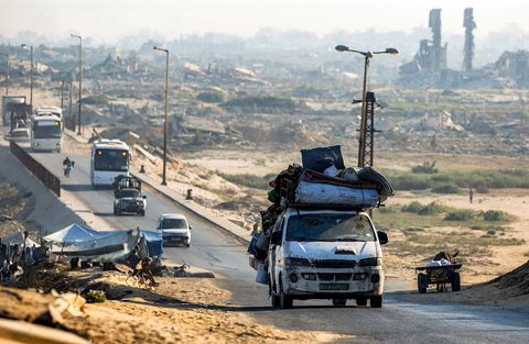 Kendaraan pengungsi melintasi bangunan yang hancur di jalan pesisir Kamp Nuseirat, Jalur Gaza tengah, Sabtu (30/08/2025).