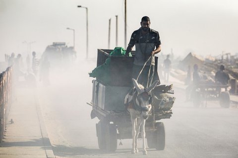 Kendaraan pengungsi melintasi bangunan yang hancur di jalan pesisir Kamp Nuseirat, Jalur Gaza tengah, Sabtu (30/08/2025).<br />AFP/ Eyad Baba.