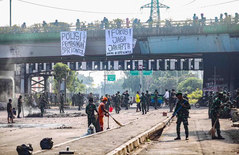 Personel TNI gabungan Kostrad dan Marinir membersihkan material sisa unjuk rasa di kawasan Mako Brimob, Kwitang, Senen, Jakarta, Minggu (31/8/2025).