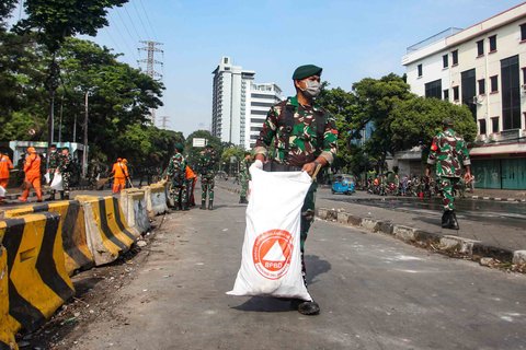 Personel TNI gabungan Kostrad dan Marinir membersihkan material sisa unjuk rasa di kawasan Mako Brimob, Kwitang, Senen, Jakarta, Minggu (31/8/2025).