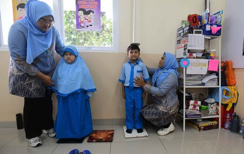 Murid sekolah dasar dicek berat dan tingginya  saat kegiatan Cek Kesehatan Gratis (CKG) di SD Prestasi Global, Depok, Jawa Barat, Senin (04/08/2025).