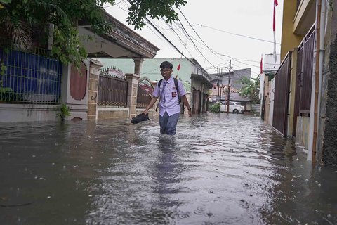 Warga melintasi genangan air di kawasan RT 10 RW 08, Kelurahan Gedong, Kecamatan Pasar Rebo, Jakarta Timur, Senin (4/8/2025
