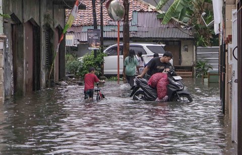 Warga melintasi genangan air di kawasan RT 10 RW 08, Kelurahan Gedong, Kecamatan Pasar Rebo, Jakarta Timur, Senin (4/8/2025