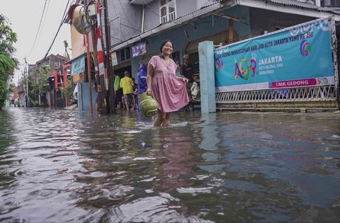 Warga melintasi genangan air di kawasan RT 10 RW 08, Kelurahan Gedong, Kecamatan Pasar Rebo, Jakarta Timur, Senin (4/8/2025