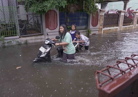 Warga melintasi genangan air di kawasan RT 10 RW 08, Kelurahan Gedong, Kecamatan Pasar Rebo, Jakarta Timur, Senin (4/8/2025