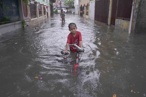 Warga melintasi genangan air di kawasan RT 10 RW 08, Kelurahan Gedong, Kecamatan Pasar Rebo, Jakarta Timur, Senin (4/8/2025