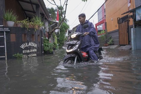 Warga melintasi genangan air di kawasan RT 10 RW 08, Kelurahan Gedong, Kecamatan Pasar Rebo, Jakarta Timur, Senin (4/8/2025