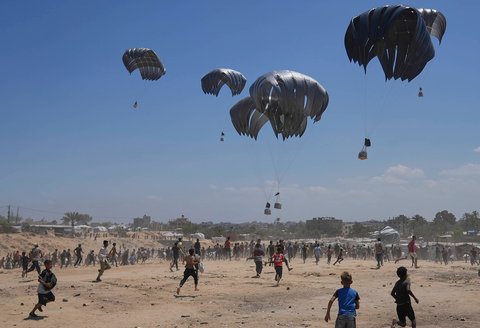 Warga Palestina berlari untuk  mengambil bantuan kemanusiaan yang dijatuhkan dengan parasut ke Zawaida di Jalur Gaza tengah, Senin (04/08/2025).