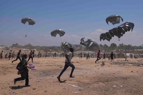 Warga Palestina berlari untuk  mengambil bantuan kemanusiaan yang dijatuhkan dengan parasut ke Zawaida di Jalur Gaza tengah, Senin (04/08/2025).