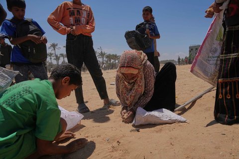 Warga Palestina mengumpulkan sisa bahan makanan dari  bantuan kemanusiaan yang dijatuhkan dengan parasut ke Zawaida, di Jalur Gaza tengah, Senin (04/08/2025).
