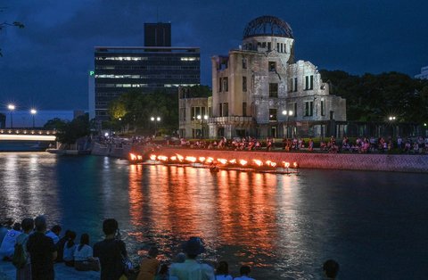 Warga menyaksikan api unggun di sepanjang Sungai Motoyasu di depan Kubah Bom Atom saat peringatan 80 tahun serangan bom atom pertama di kota Hiroshima, Jepang, elasa (05/08/2025).