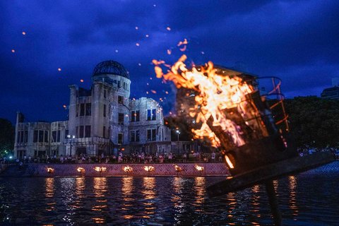 Warga menyalakan unggun di sepanjang Sungai Motoyasu di depan Kubah Bom Atom saat peringatan 80 tahun serangan bom atom pertama di kota Hiroshima, Jepang, Selasa (05/08/2025).
