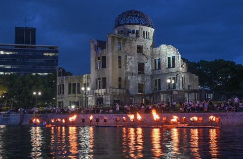 Warga menyaksikan api unggun di sepanjang Sungai Motoyasu di depan Kubah Bom Atom saat peringatan 80 tahun serangan bom atom pertama di kota Hiroshima, Jepang, elasa (05/08/2025).