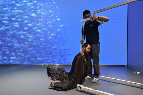 Seorang pria memegang robot humanoid di Robot Mall di Beijing Kamis (06/08/2025) waktu setempat