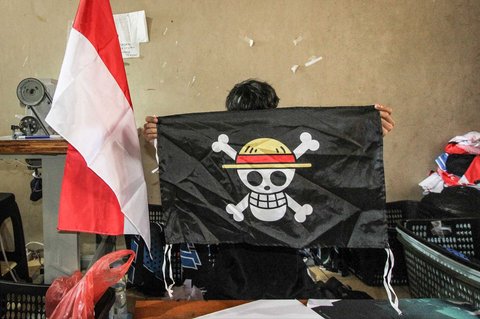 Seorang pekerja memegang replika bendera bajak laut dari anime Jepang One Piece yang dibuat pada industri konveksi di Karanganyar, Jawa Tengah, Rabu (06/08/2025).