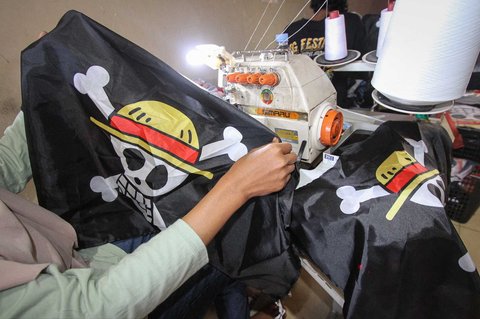 Seorang pekerja memegang replika bendera bajak laut dari anime Jepang One Piece yang dibuat pada industri kecil konveksi di Karanganyar, Jawa Tengah, Rabu (06/08/2025).