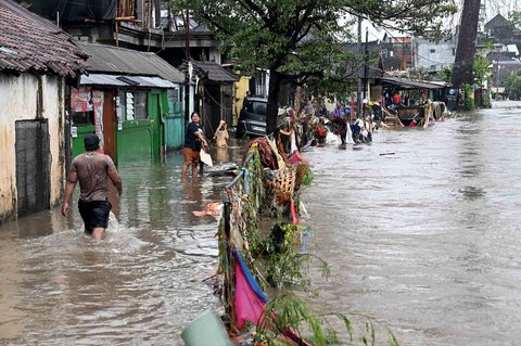 Warga  berjalan melewati  banjir  yang merendam pemukiman mereka di  Denpasar, Bali, Rabu (10/09/2025).