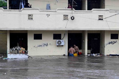 Warga  berdiri di depan rumahmya yang terendam banjir di Denpasar, Bali, Rabu (10/09/2025).