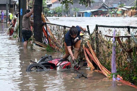 Seorang warga mengambil motornya yang terjatuh saat banjir di Denpasar, Bali, Rabu (10/09/2025).