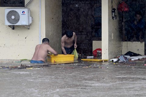 Warga  berdiri di depan rumahnya yang terendam banjir di Denpasar, Bali, Rabu (10/09/2025).
