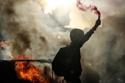 Seorang pengunjuk rasa menyalakan  api asap di dekat barikade yang terbakar dalam aksi gerakan nasional "Mari Kita Blokir Semuanya&rdquo; di di Paris Prancis, Selasa (10/09/2025).