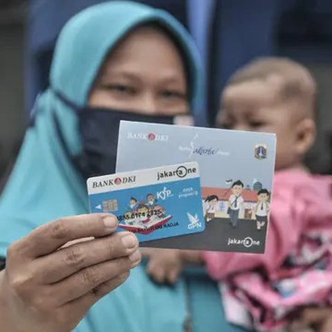 Orangtua dari anak penerima saat menunjukkan KJP yang baru diterima di kawasan Matraman, Jakarta, Selasa (24/11/2020). Penyaluran KJP plus tahap kedua ini menggunakan data baru berdasarkan pe