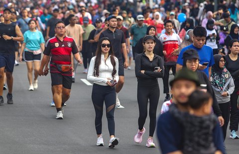 Warga berolahraga dan jalan santai di arena car free day (CFD) Jalan Thamrin, Jakarta, Minggu (14/9/2025).